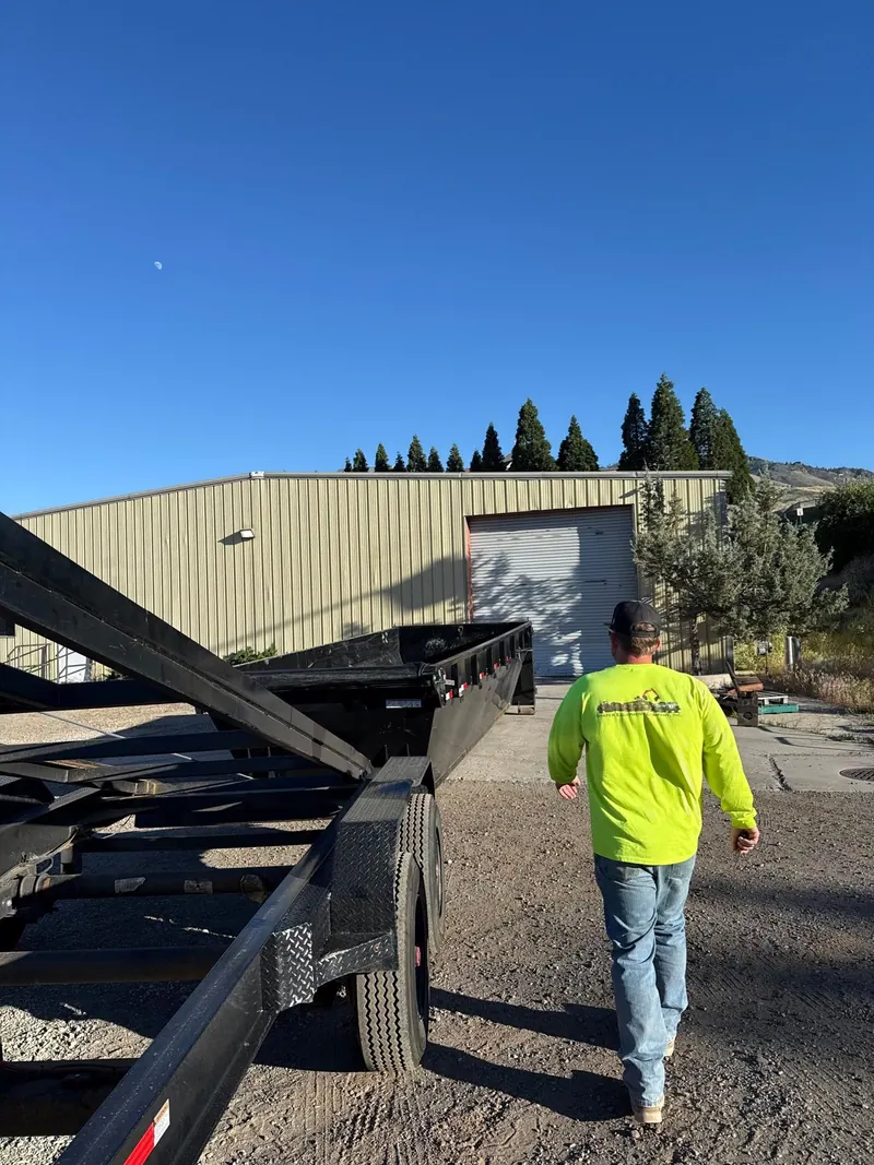A crew member in a bright shirt walking to a commercial building past the trailer