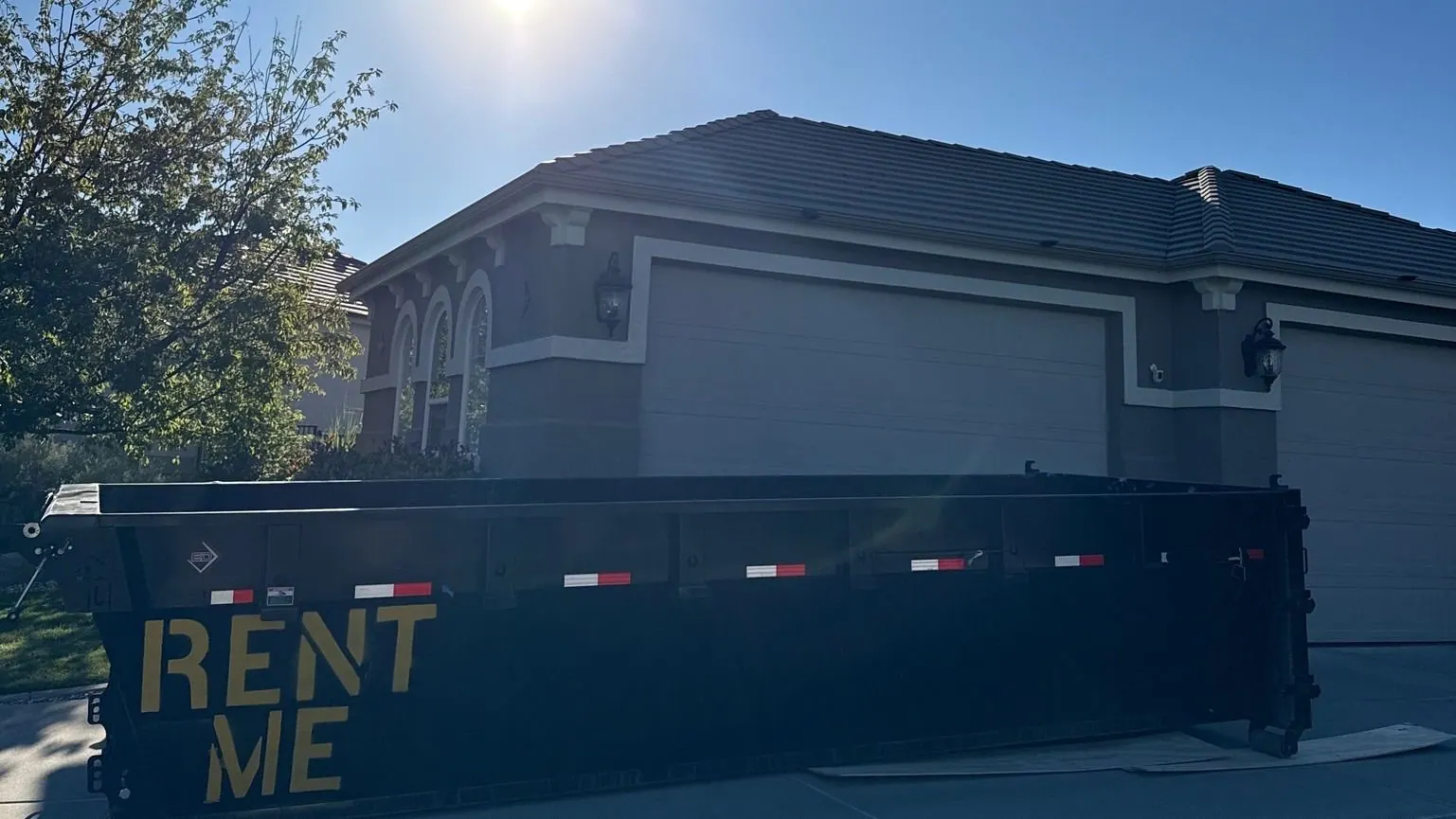A roll-off dumpster set at the curb in front of a house