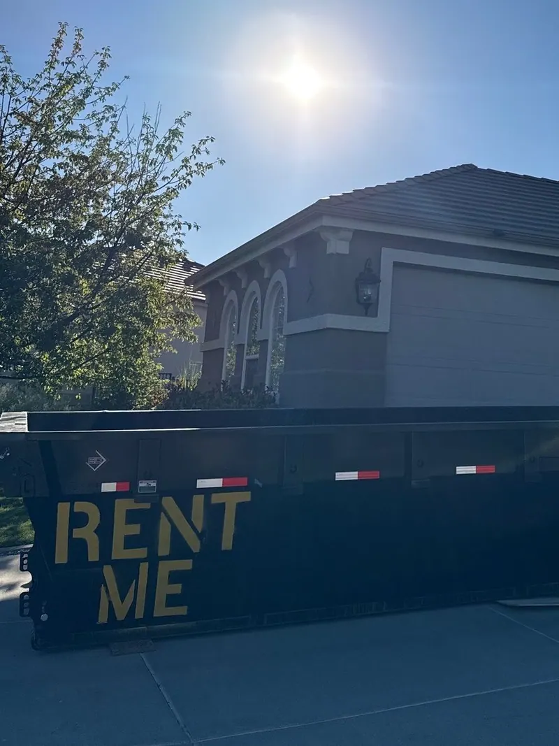 A roll-off dumpster set at the curb in front of a house