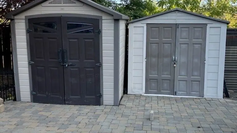 Two plastic storage sheds on a backyard paver patio