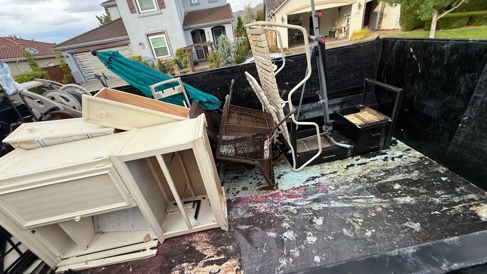 The dump trailer loaded with dressers chairs and patio furniture in a neighborhood