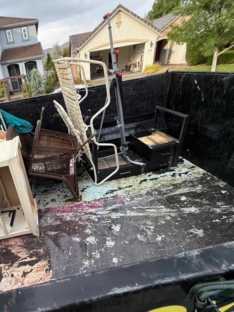 The dump trailer loaded with dressers chairs and patio furniture in a neighborhood