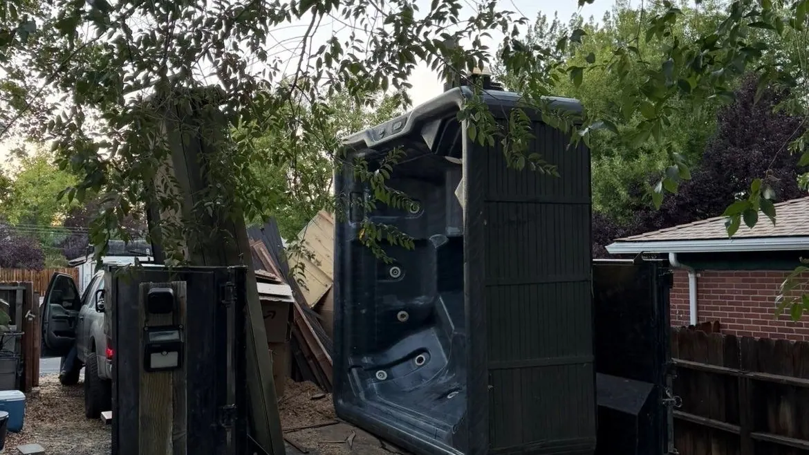 An old hot tub loaded upright on a trailer