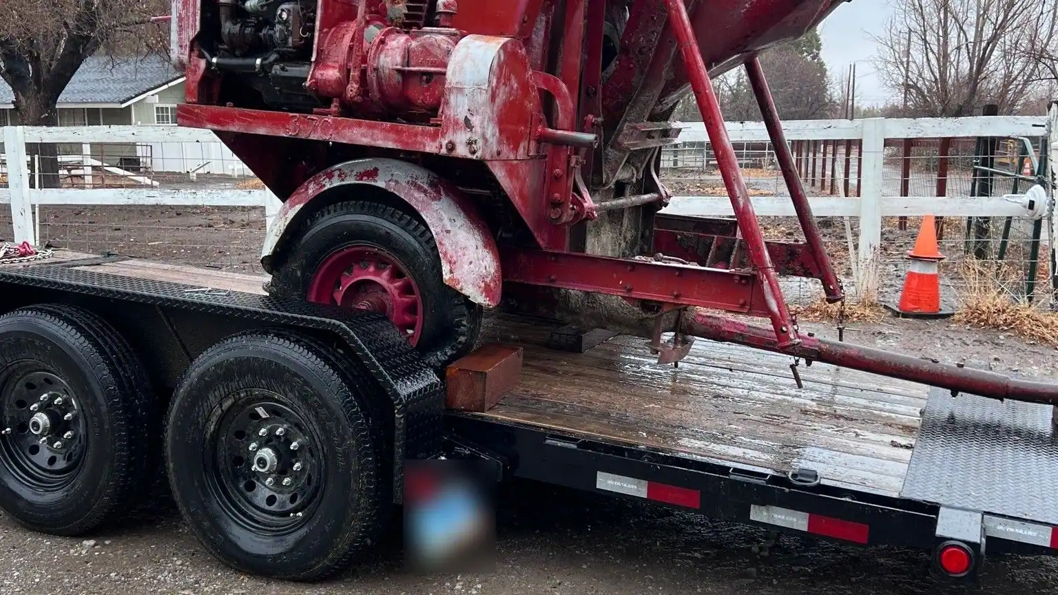 An old red machine strapped onto a flatbed trailer