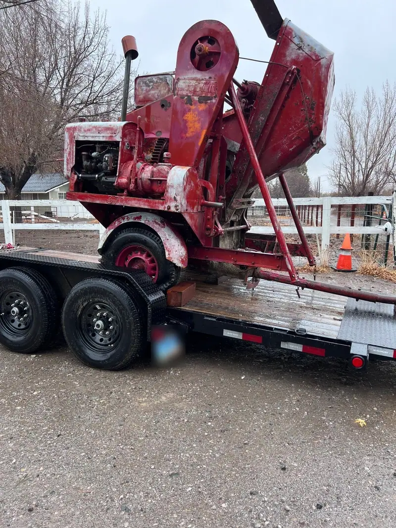 An old red machine strapped onto a flatbed trailer