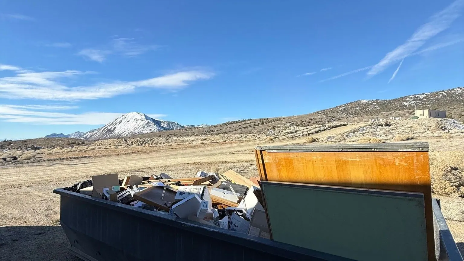 A roll-off dumpster loaded with furniture and debris