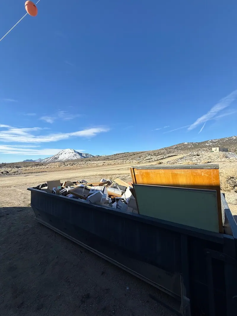 A roll-off dumpster loaded with furniture and debris