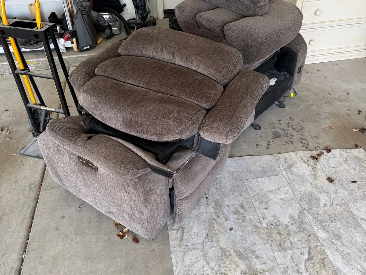 A garage with a brown recliner sofa and a rug on the floor