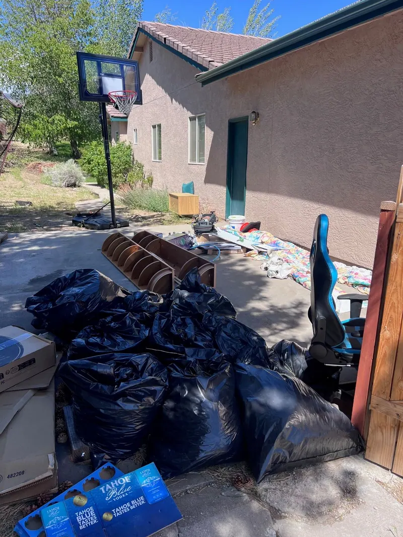 Trash bags and boxes piled beside a house