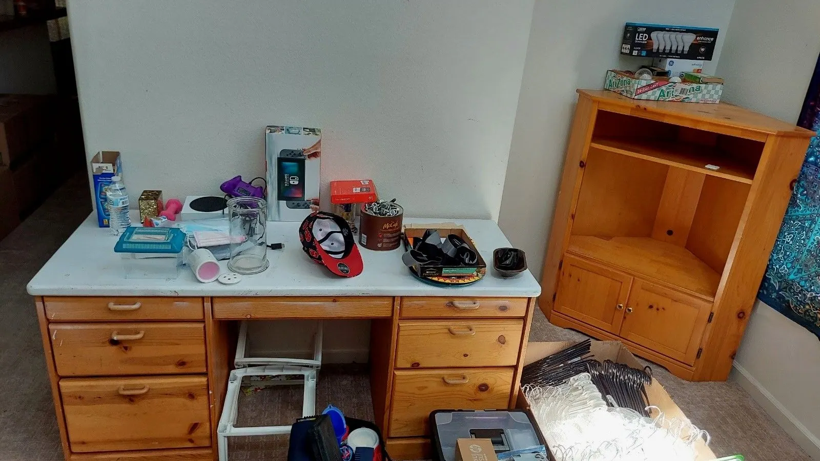 A bedroom desk and cabinet covered in leftover belongings