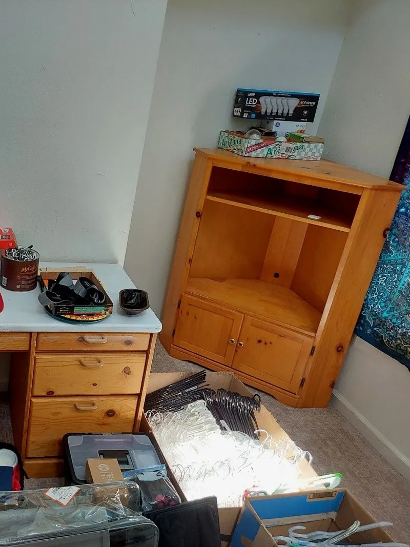 A bedroom desk and cabinet covered in leftover belongings