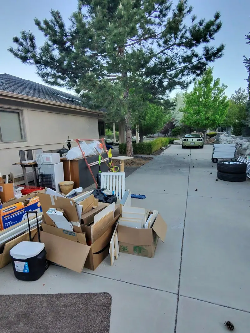 Boxes bins and furniture set out on a driveway for pickup