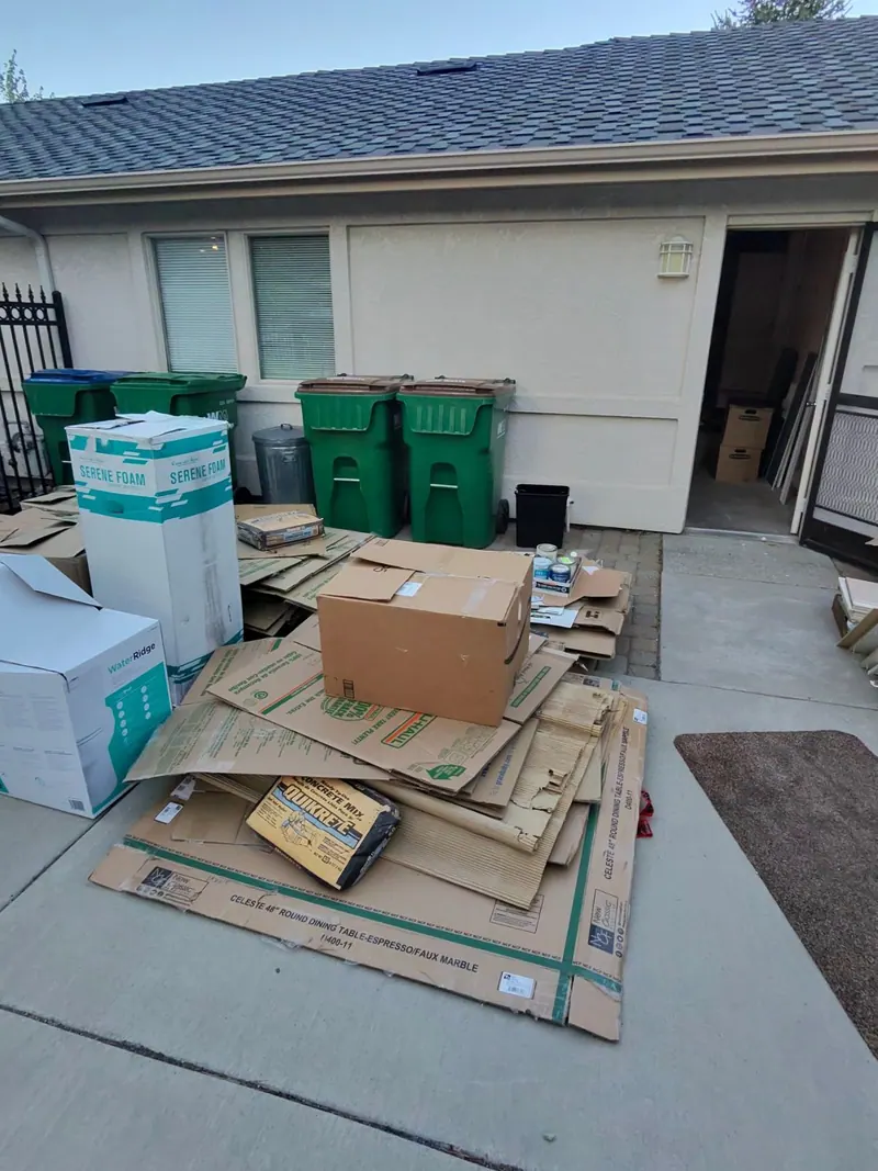 Flattened cardboard and boxes stacked at a garage door