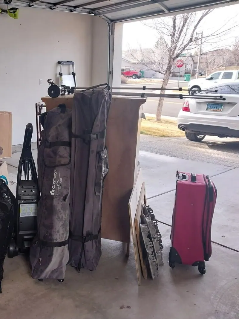 A loveseat bags tables and luggage lined up in an open garage