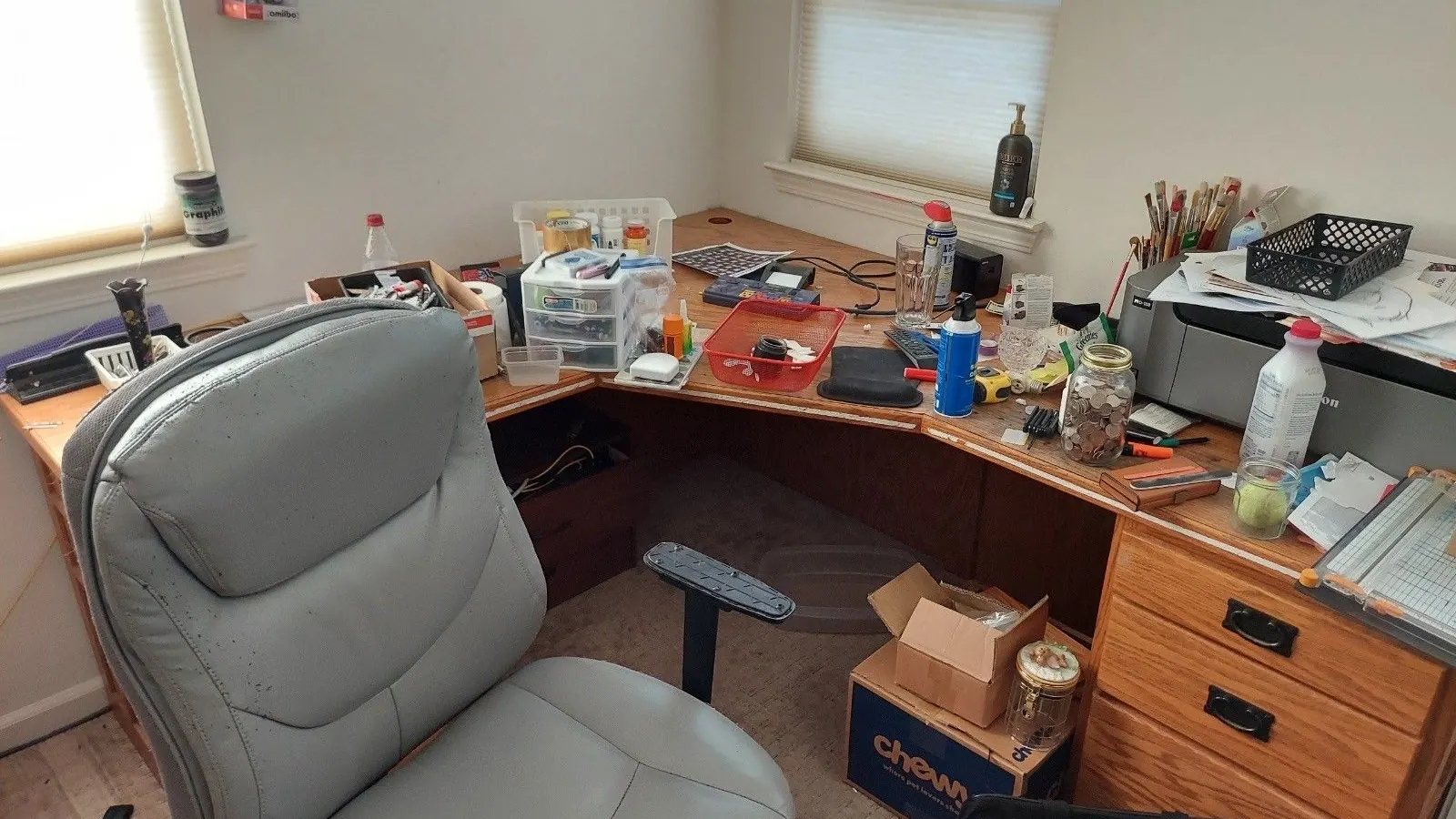 An office corner desk and chair covered in supplies