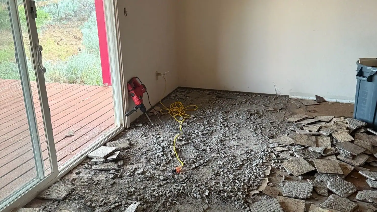 Broken floor tile piled across a room by a sliding door