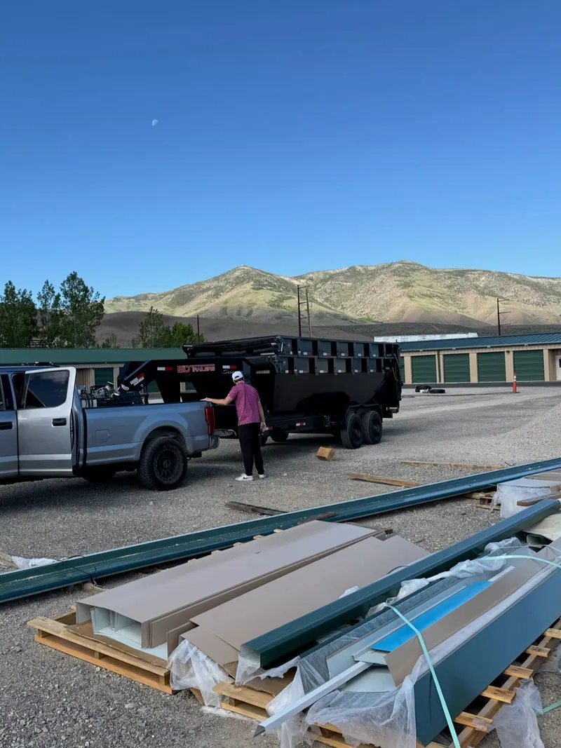 The pickup and dump trailer at a storage lot beside a stack of building materials