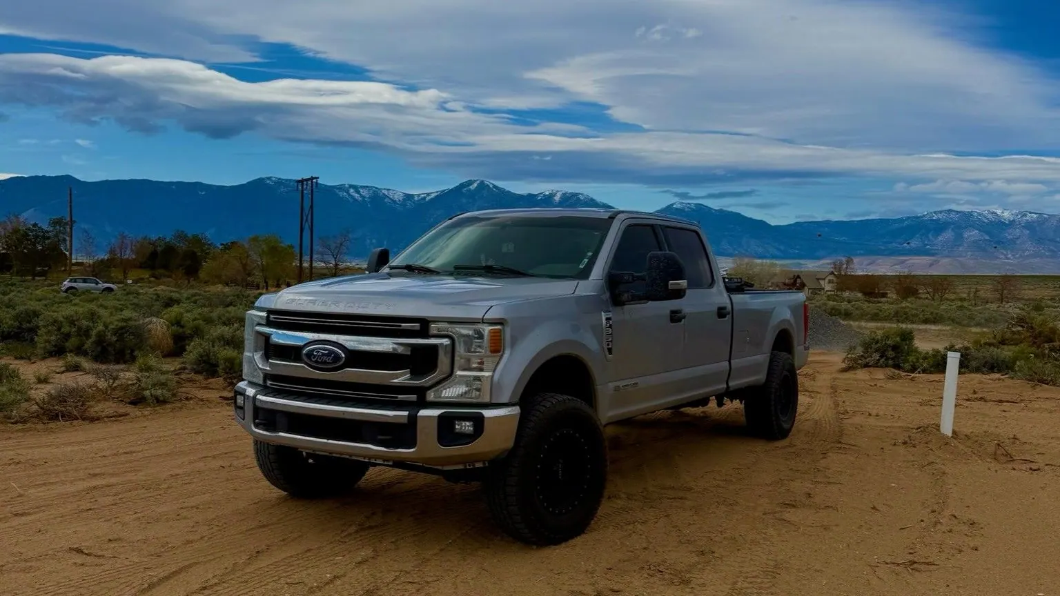 The silver Ford pickup parked on a dirt lot under a big sky