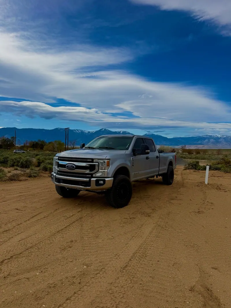 The silver Ford pickup parked on a dirt lot under a big sky